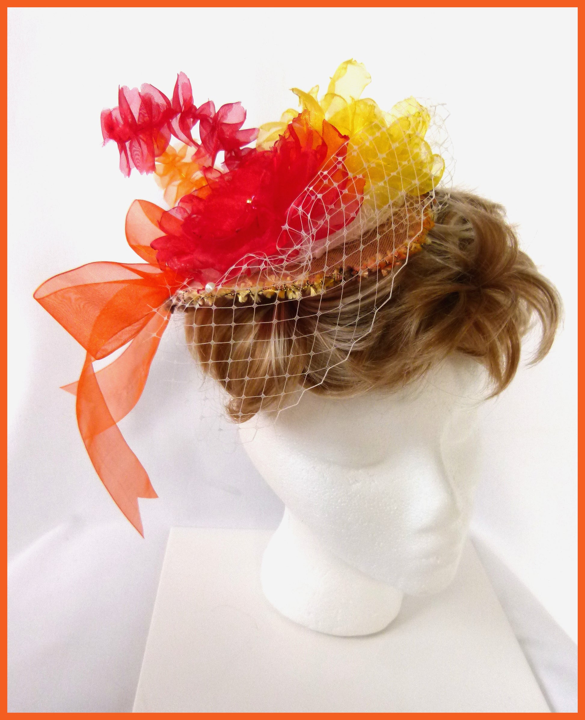 Firefly Fascinator with red and yellow beaded organza flowers, organza feather and bow and ivory veiling